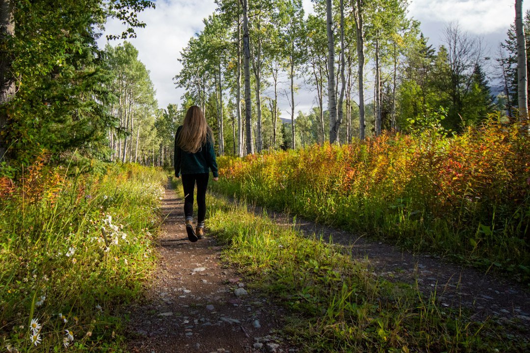 Mujer camina al aire libre entre árboles y vegetación